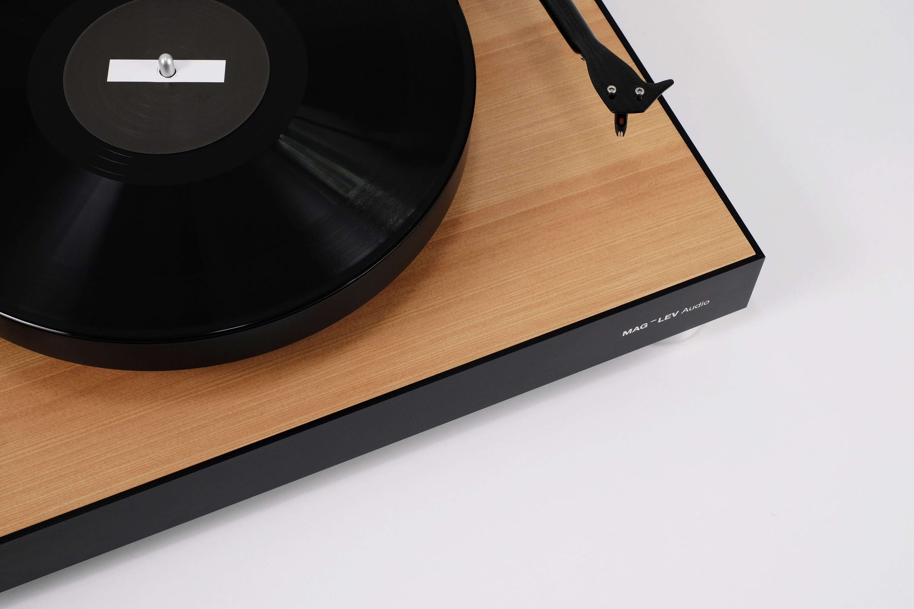 Top detail of the MAG-LEV Audio ML1 Wood turntable showing the tonearm, vinyl record and natural wood finish.